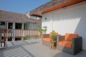 a patio with two chairs and a house at Cocomo Maldives in Himmafushi