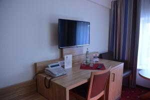 a room with a desk with a phone and a television at Altstadthotel Harburg in Hamburg