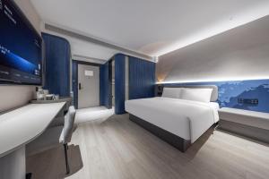 una camera da letto con un letto, una scrivania e una TV di Atour Light Hotel Nanjing Xinjiekou Hanzhongmen Subway Station a Nanjing