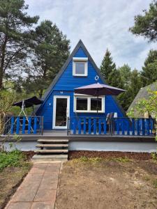 a blue house with a porch and an umbrella at Ferienhaus am Helenesee 14 in Frankfurt Oder