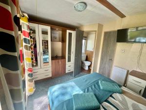 a bedroom with a blue bed and a bathroom at Tattershall Lakes 2 bedroom,6 berth Holiday home with hot tube in Tattershall