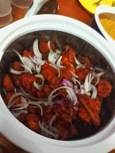 a bowl of food with meat and onions on a table at Smiley Homestay Family-Friendly 3BR in Kodaikānāl