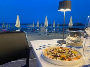 a table with a bowl of food on a table with a beach at Hotel Baia Marina in Cupra Marittima