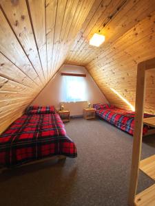 a attic bedroom with two beds and a wooden ceiling at Horská Chata Martin in Loučná pod Klínovcem
