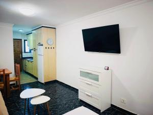 a kitchen with two stools and a tv on a wall at Cozy 2-Bed & Sofa-bed Studio - Pool Pets Wifi in Los Cristianos