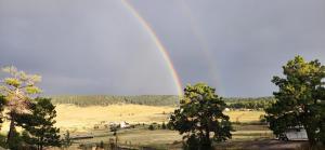 a rainbow in the sky over a field with trees at Rustic Treehouse in Peyton