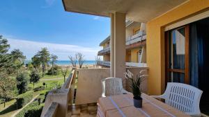 a balcony with a table and chairs and a view of the ocean at Condominio Carina Sud in Bibione