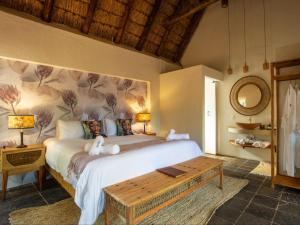 a bedroom with a large bed and a table at Etnika Manor House in Hoedspruit