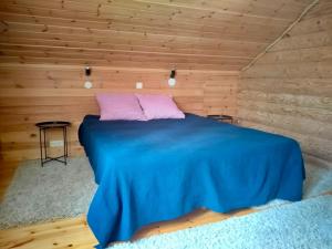 a bedroom with a blue bed in a wooden wall at Huvila Kivitasku - Arkea pakoon in Kutemajärvi