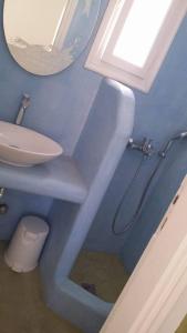 ein Badezimmer mit einem Waschbecken, einem WC und einem Spiegel in der Unterkunft Pension Christina in Aegiali