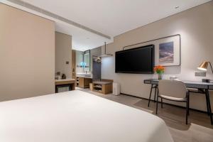 una camera d'albergo con un letto, una scrivania e una TV di Atour Hotel Qingdao Taidong Beer Street a Qingdao