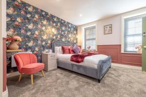 a bedroom with a bed and a red chair at Boutique Stays at 56 in Newtownards
