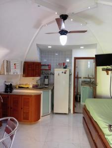 a kitchen with a white refrigerator and a table at Chalé em Búzios 100m da Praia de Tucuns in Búzios