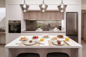 a kitchen with a white island with plates of food on it at Theatro Living in Elegance - Luxury Apartments in Hersonissos in Hersonissos