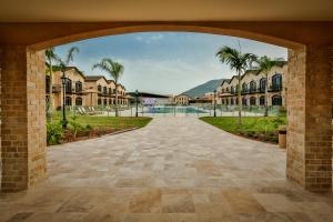 伊索德達哈馬拉的住宿－Galilion Hotel，拱门通往带房屋和棕榈树的庭院