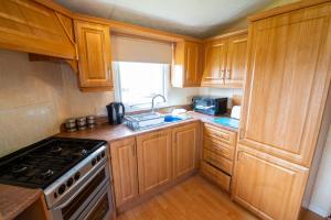a kitchen with wooden cabinets and a stove top oven at WW252 Parkdean Camber Sands in Camber