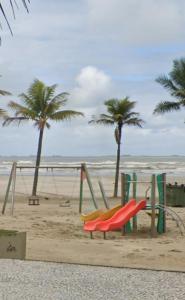 Un grupo de columpios en una playa con palmeras. en Apê na PG only 150 Metros da Praia, en Praia Grande