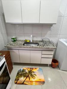 Una cocina con fregadero y una alfombra de palmera en el suelo. en Apê na PG only 150 Metros da Praia, en Praia Grande 21 fotos más