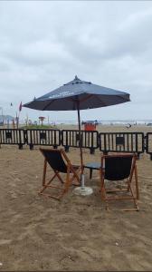 una mesa y dos sillas bajo una sombrilla en la playa en Apê na PG only 150 Metros da Praia, en Praia Grande