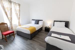 een slaapkamer met 2 bedden en een rode stoel bij Luxurious 5 bedrooms apartment and a living room in 7 Sydenham Road, Oxbridge, Stockton, Stockton-on-Tees, TS18 4DG in Stockton-on-Tees
