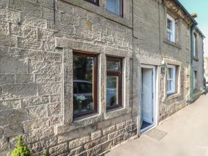 ein Backsteingebäude mit zwei Fenstern und einer Tür in der Unterkunft Coniston Cottage in Bakewell