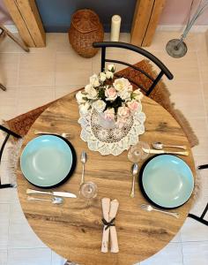 a wooden table with two plates and a vase of flowers at Gold Moon Apartment in Kecskemét