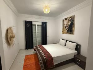 a bedroom with a bed and a painting on the wall at Elegant apartment in Essaouira in Essaouira
