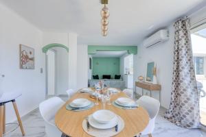 Un comedor con una mesa de madera y sillas blancas. en Villa Helvétie - Welkeys, en Toulon