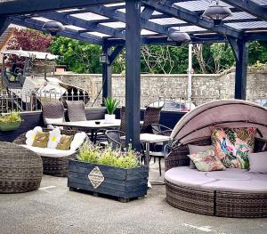 a patio with wicker chairs and tables and a pergola at Beaufort Hotel in Inverness