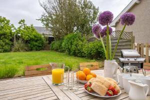 een houten tafel met borden met eten en sinaasappelsap bij Cae-Calch in Morfa Nefyn