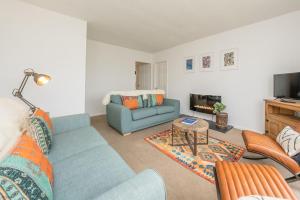 een woonkamer met een blauwe bank en een tv bij Cae-Calch in Morfa Nefyn