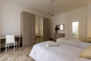 a white bedroom with two beds and a desk at Artist Apartment in Mantova