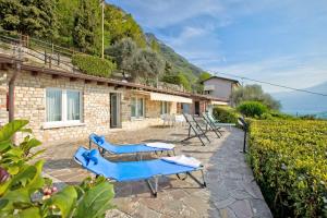 un patio con sillas azules y una casa en Gargnano Apartments, en Gargnano