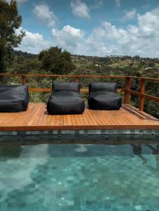 una terraza de madera con 2 sillas junto a una piscina en Arroyo & Grapes, en Campinas