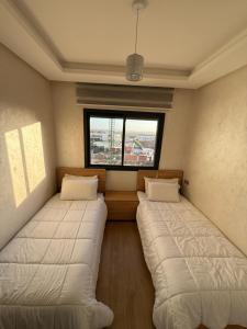 two beds in a room with a window at Appartement a zenata ain-harrouda casablanca in Mohammedia