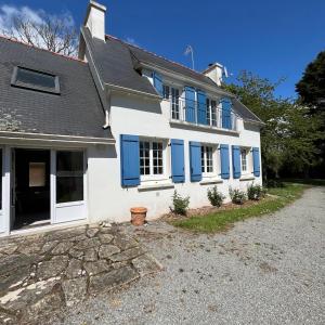 een wit huis met blauwe ramen en een oprit bij Détente à la mer Blanche in Fouesnant