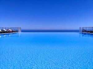 una grande piscina di acqua blu con persone sdraiate su di essa di Luxueux appartement - vue mer - piscine - free parking - Monaco a Cap d'Ail