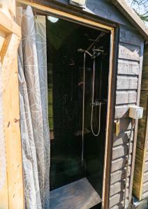 a shower in a shed with a shower curtain at Bluebell bell tent The Roaches in Upper Hulme
