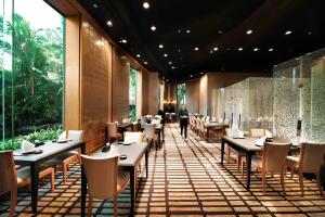 a restaurant with tables and chairs and a person walking in the background at Hilton Kuala Lumpur in Kuala Lumpur +116 photos