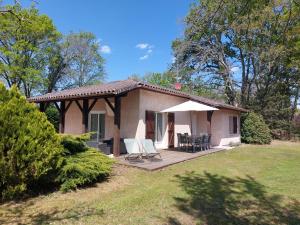 a small house with a deck and a table and chairs at L'Eyre de vacances -Proche Lac Arjuzanx - jeux - terrasse - plancha - in Luglon