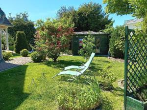 a white chair sitting in the grass in a yard at Ferienwohnungen im Klönhus in Prerow