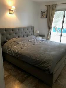 a bed in a bedroom with a large window at Jardin d’Uzès - Climatisée avec piscine in Saint-Quentin-la-Poterie
