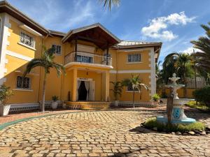 a yellow house with a fountain in front of it at Villa Arcadia in Nosy Be