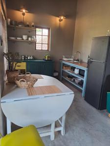 a kitchen with a white table and a refrigerator at A cozy, artistic suburban-stay at Alice in Africa in Rooihuiskraal +25 photos