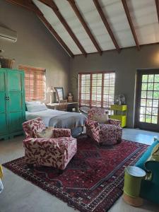 a bedroom with a bed and a couch and chairs at A cozy, artistic suburban-stay at Alice in Africa in Rooihuiskraal