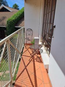 a patio with a table and chairs on a balcony at A cozy, artistic suburban-stay at Alice in Africa in Rooihuiskraal