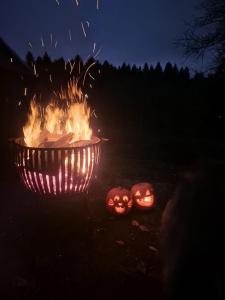 two pumpkins sitting next to a fire pit at night at Bracken Barns Glamping & Massage in Minishant