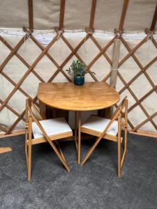 a wooden table and chairs with a potted plant on it at Bracken Barns Glamping & Massage in Minishant +31 photos
