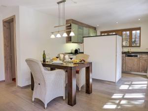 a kitchen with a wooden table with chairs and a refrigerator at Apartment Chalet Smaragd-3 by Interhome in Grindelwald