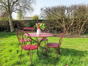einen Tisch mit Stühlen und eine Vase mit Blumen darauf in der Unterkunft Holiday Home Dolce Vita by Interhome in Plouha